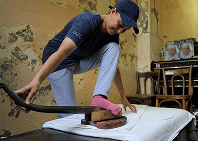 مصرية لا تزال تستخدم "مكواة القدم" في كي ملابس زبائنها